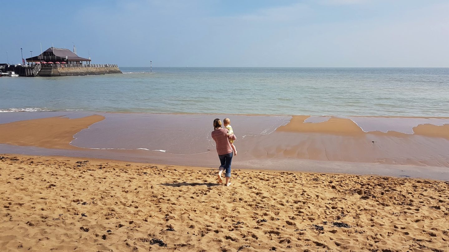 Mum carrying baby towards the sea