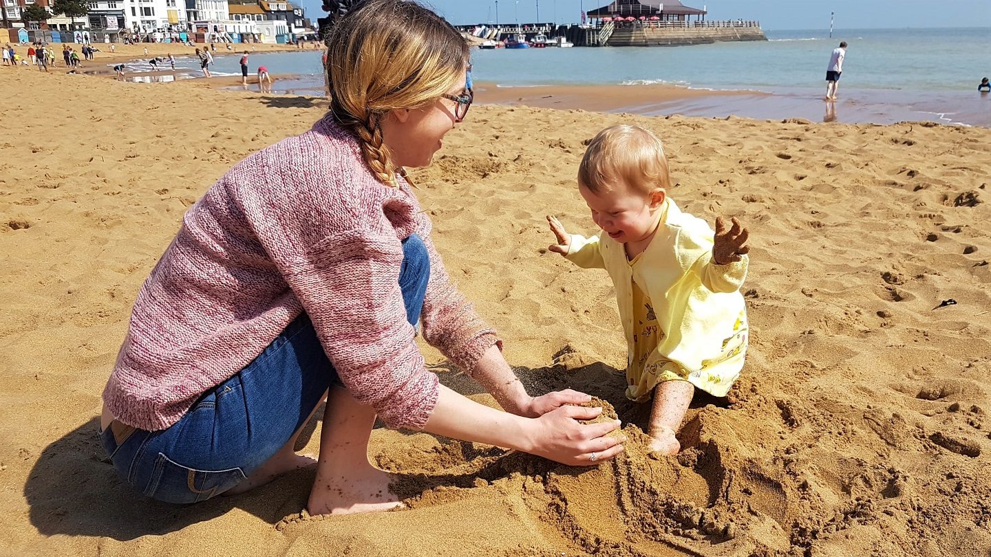Mum and toddler making a sandcastle
