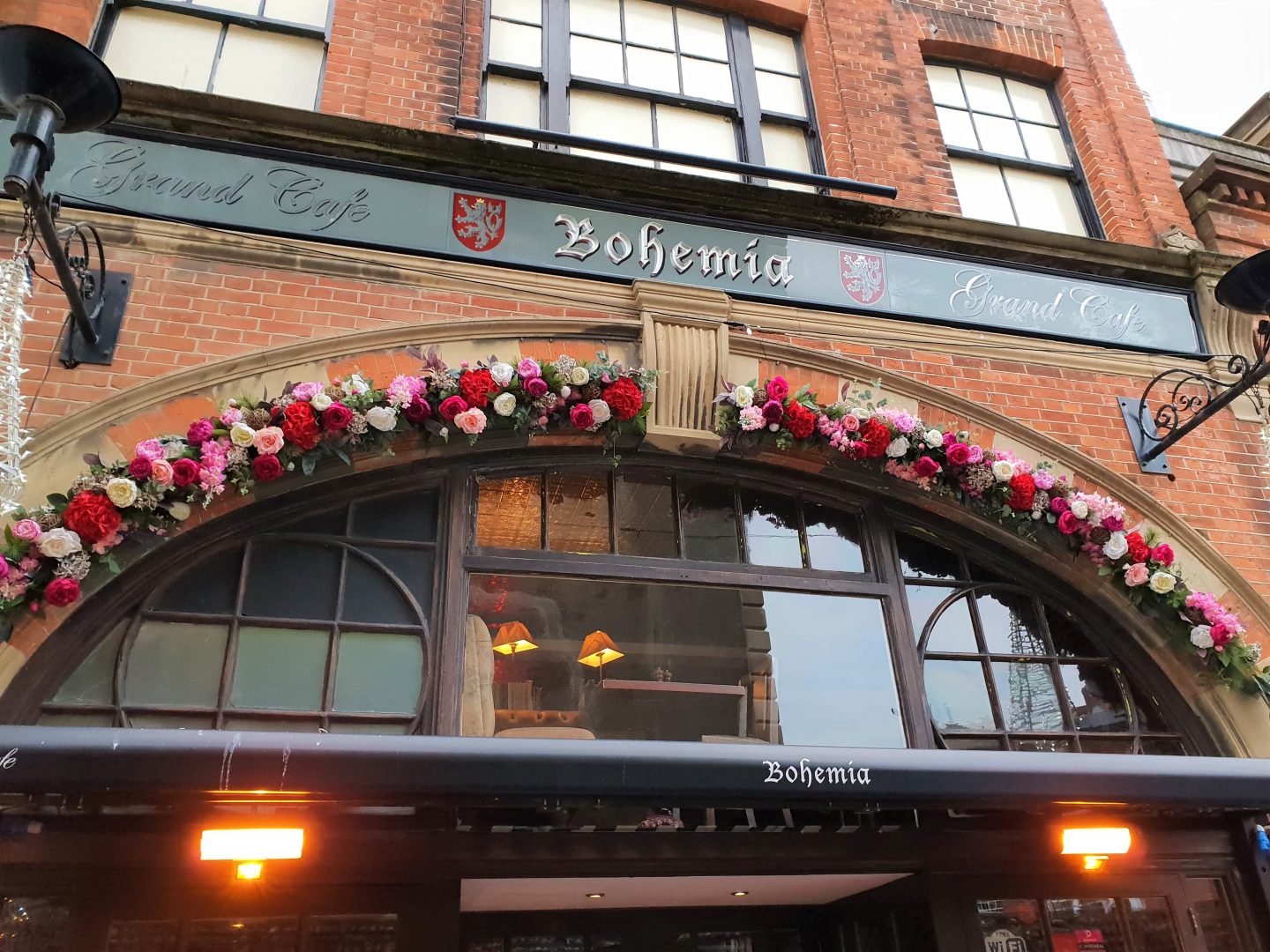 Frontage of Bohemia Brighton, adorned with flowers on the arch stonework