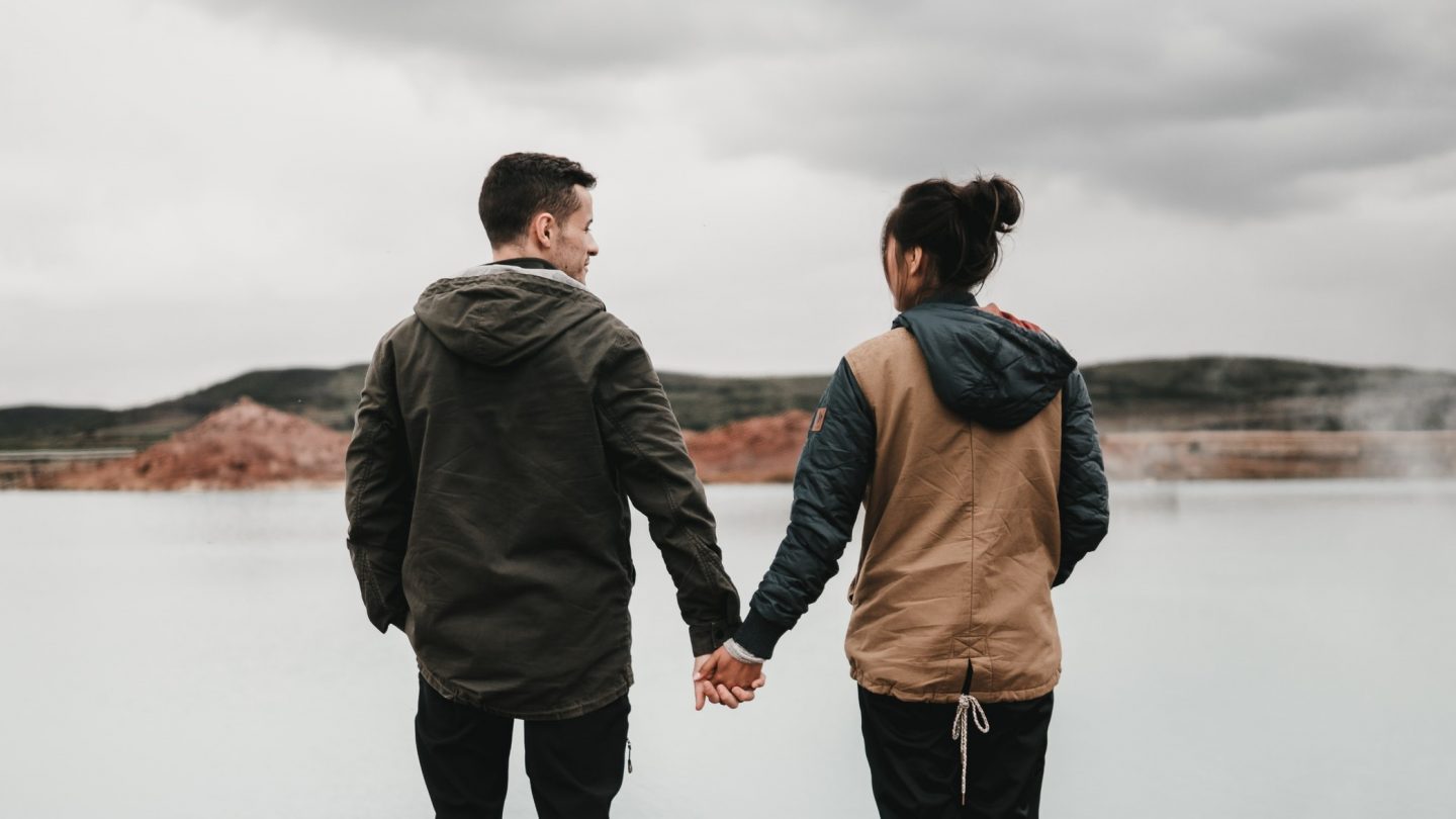 A couple by a lake holding hands